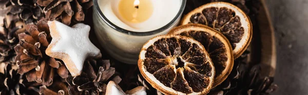 Panoramic shot of scented candle with cookie and pine cones — Stock Photo