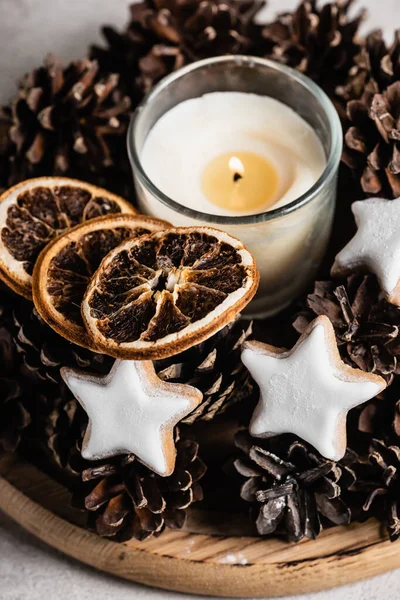 Vela perfumada com cones de pinheiro, fatias de laranja secas e biscoitos — Fotografia de Stock