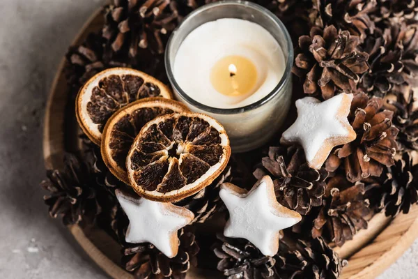 Vue rapprochée de la bougie parfumée avec tranches d'orange séchées, cônes de pin et biscuits — Photo de stock