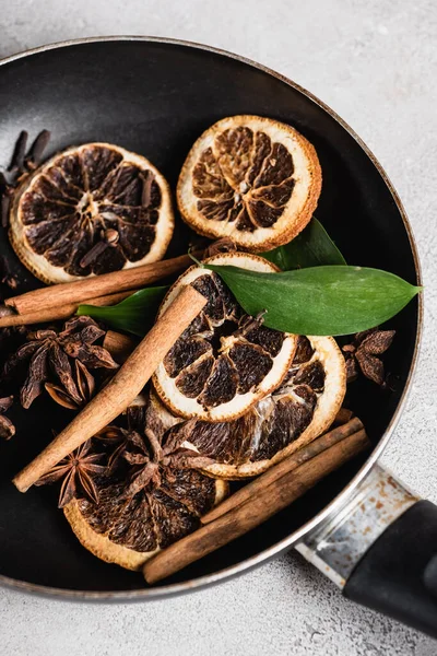 Rodajas de naranja secas y especias en sartén sobre fondo gris - foto de stock