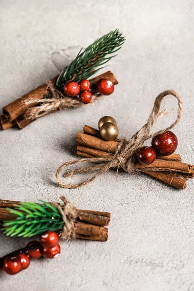 Cinnamon sticks with red beads on textured and grey background — Stock Photo