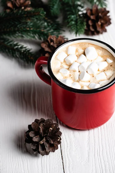 Foyer sélectif de tasse rouge de cacao près du cône de pin sur fond en bois — Photo de stock