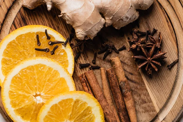 Close up view of orange slices, spices and ginger root on wooden plate — Stock Photo