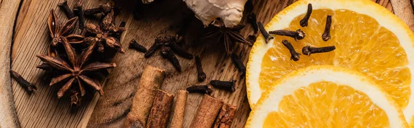 Panoramic shot of orange slices and spices on wooden background — Stock Photo