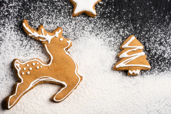 Vista superior de cookies em forma de veado, pinheiro e estrela com açúcar em pó — Fotografia de Stock