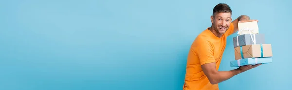 Happy man in t-shirt holding wrapped presents on blue, banner — Stock Photo