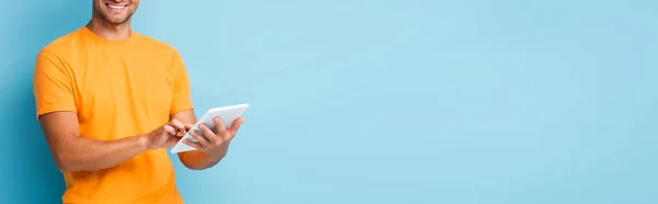 Vista cortada de homem feliz em t-shirt usando tablet digital em azul, banner — Fotografia de Stock