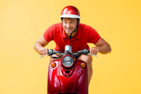 Homem feliz no capacete montando scooter vermelho isolado no amarelo — Fotografia de Stock
