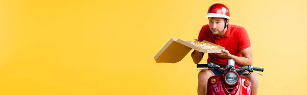 Livreur dans casque équitation scooter et tenant pizza en boîte sur jaune, bannière — Photo de stock