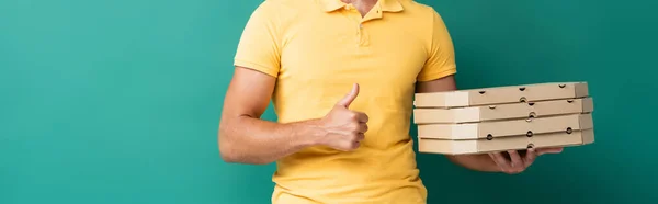 Cropped view of delivery man holding pizza boxes and showing thumb up on blue, banner — Stock Photo