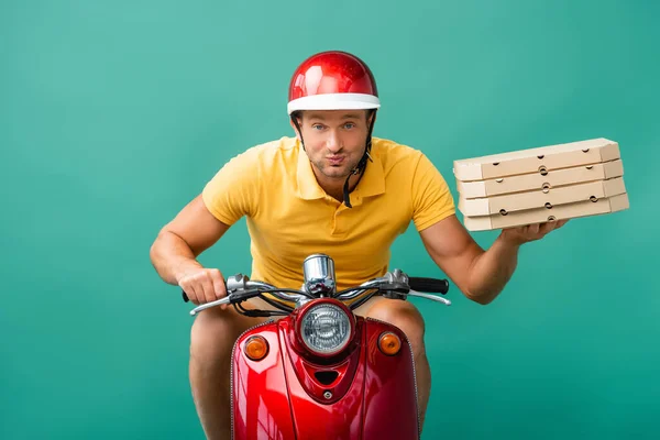 Homem de entrega focado no capacete equitação scooter enquanto segurando caixas de pizza em azul — Fotografia de Stock