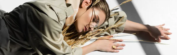 Jovem mulher em copos deitado perto de cacho de trigo no branco, banner — Fotografia de Stock