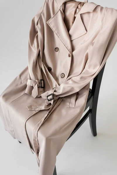 Stilvoller Trenchcoat auf Stuhl und weißem Hintergrund — Stockfoto