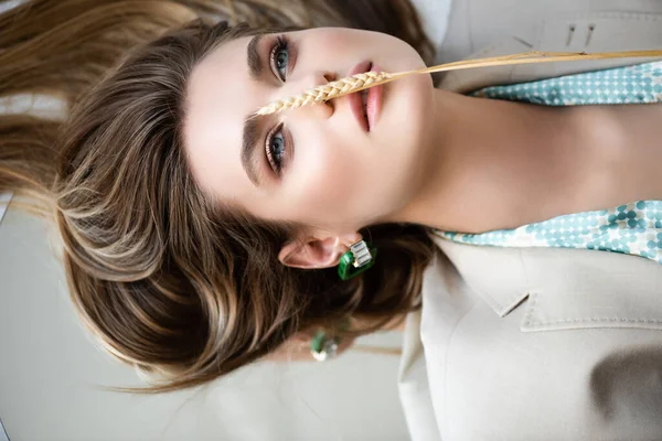 Top view of barley spikelet on face of young model lying on white — Stock Photo