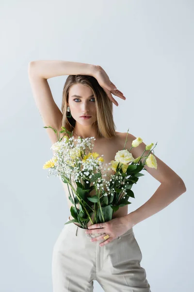 Modello giovane con mazzo di fiori in pantaloni in posa su bianco — Foto stock