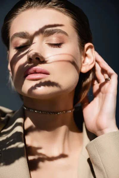 Espiguillas de trigo sombras en la cara de la mujer joven con los ojos cerrados sobre fondo gris oscuro - foto de stock