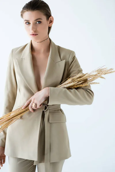 Jeune femme en beige tenue formelle exploitation blé mûr sur blanc — Photo de stock
