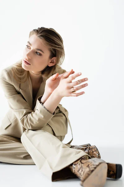 Young model in beige suit and boots with animal print posing on white — Stock Photo