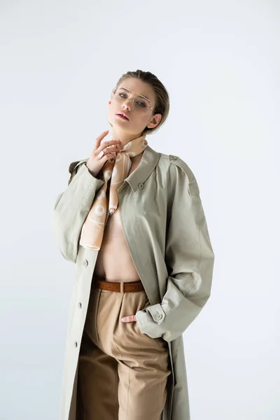 Jeune modèle en lunettes, trench coat et écharpe posant isolé sur blanc — Photo de stock