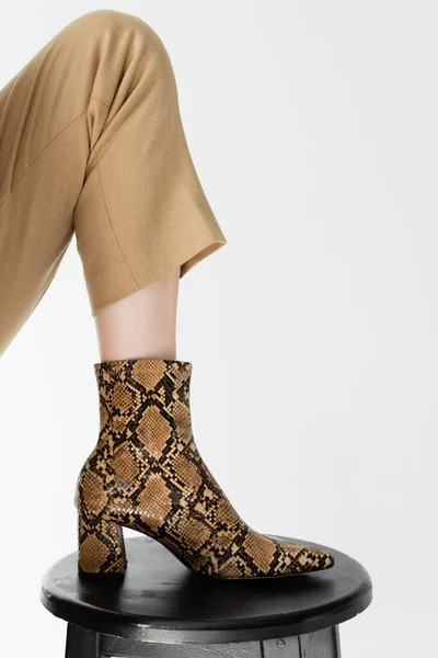 Abgeschnittene Ansicht des weiblichen Beines in Schuhen mit Animal Print auf Hocker isoliert auf weiß — Stockfoto