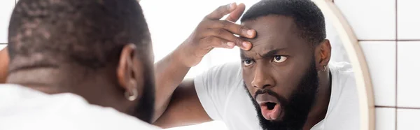 Panoramic shot of afro-american man looking at wrinkles in mirror — Stock Photo