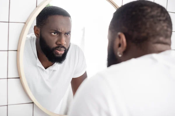 Sério afro-americano homem olhando para a reflexão no espelho — Fotografia de Stock