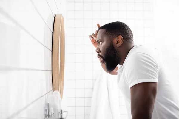 Vista lateral do homem afro-americano olhando para rugas no espelho — Fotografia de Stock