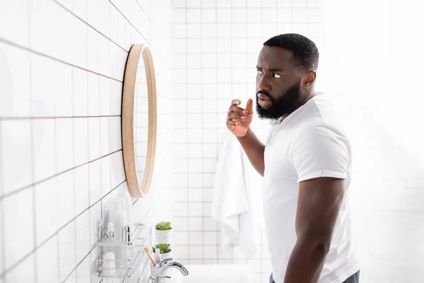 Afro-american man looking at face in mirror — Stock Photo