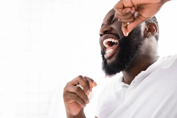 Hombre afroamericano usando hilo dental en el baño - foto de stock