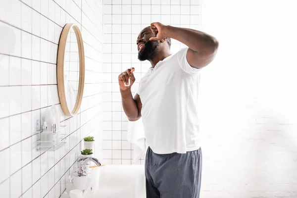 Afro-américain utilisant de la soie dentaire et se regardant dans un miroir — Photo de stock