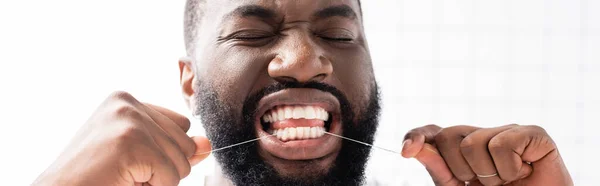 Panoramic shot of afro-american man with closed eyes using dental floss — Stock Photo