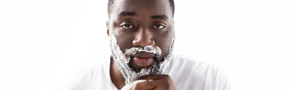 Panoramic shot of afro-american man with shaving foam on face looking at camera — Stock Photo