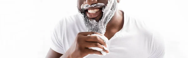 Vista panorámica del hombre afroamericano sonriente con espuma de afeitar en la cara mirando a la cámara - foto de stock