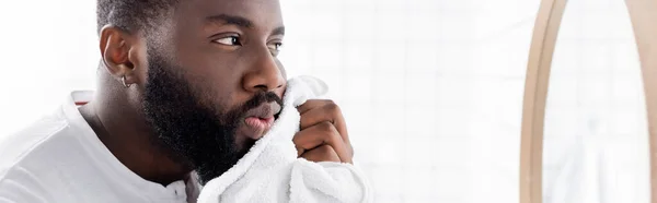 Plano panorámico de hombre afroamericano secando barba con toalla - foto de stock