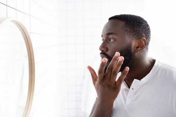 Hombre afroamericano aplicando cura para fortalecer el crecimiento de la barba - foto de stock