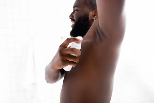 Sorrindo afro-americano homem com mão para cima usando desodorizante — Fotografia de Stock