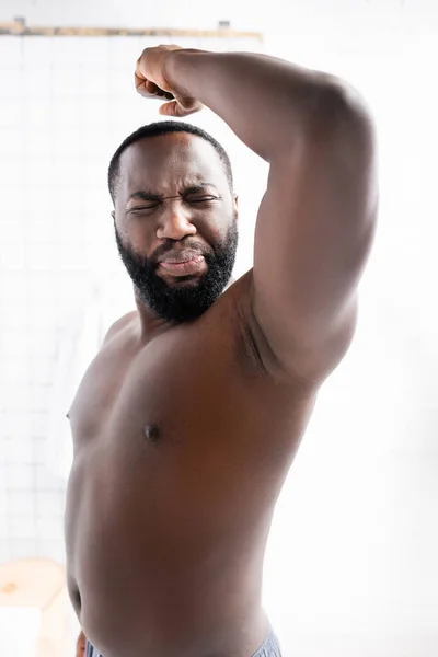 Hombre afroamericano levantando la mano y haciendo muecas por el mal olor - foto de stock