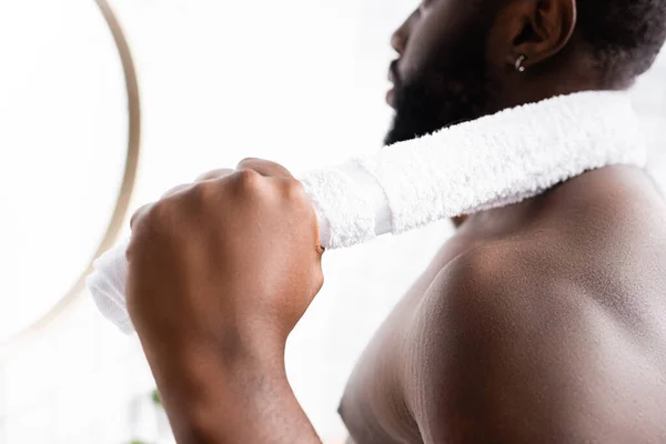 Vue partielle d'un homme afro-américain sérieux regardant dans un miroir avec une serviette derrière le cou — Photo de stock