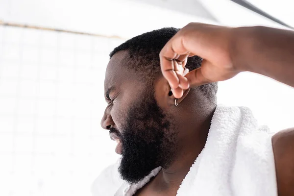 Retrato de hombre afroamericano limpiando oídos con dolor - foto de stock
