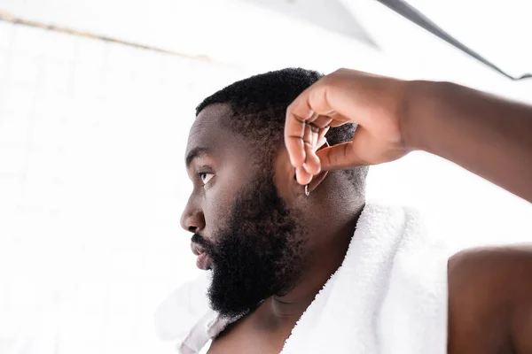 Visão lateral do homem afro-americano limpando orelhas com auricular — Fotografia de Stock