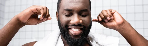 Panoramic shot of afro-american man cleaning ears with ear sticks — Stock Photo