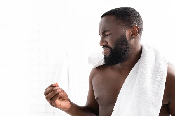 Hombre afro-americano mirando el palo de la oreja con asco - foto de stock