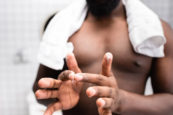 Selective focus of afro-american man using cure for strengthening beard growth — Stock Photo