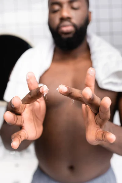Selective focus of afro-american man using cure for strengthening beard growth — Stock Photo
