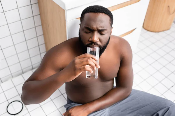 Uomo afro-americano che soffre di postumi di sbornia e acqua potabile — Foto stock