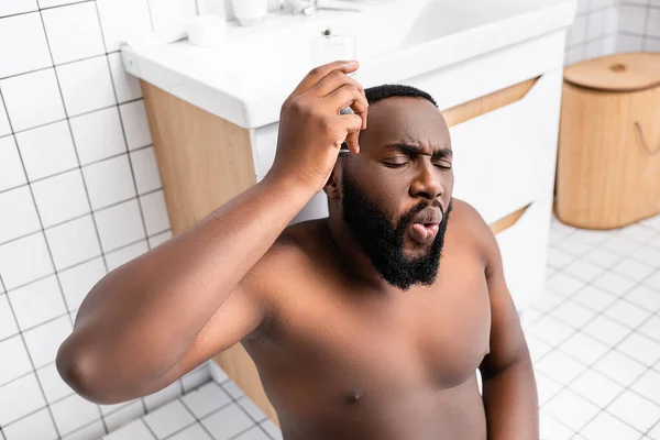 Afro-american man suffering from hangover and feeling relief from cold glass of water — Stock Photo