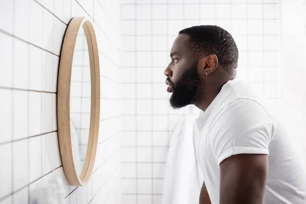 Seitenansicht eines ernsten afroamerikanischen Mannes, der in den Spiegel schaut — Stockfoto