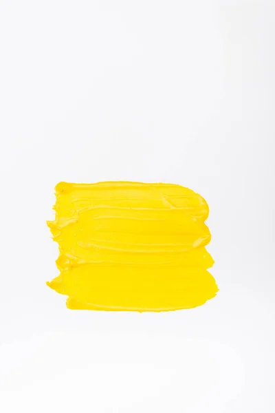 Vue de dessus des coups de pinceau jaunes colorés abstraits sur fond blanc — Photo de stock