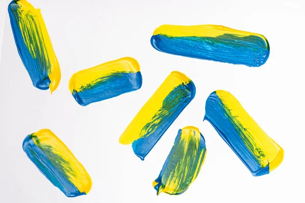 Top view of abstract colorful yellow and blue paint brushstrokes on white background — Stock Photo