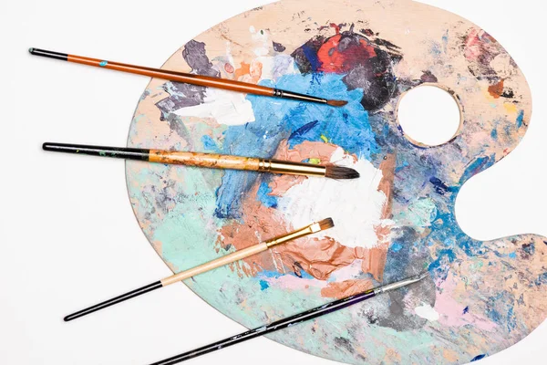 Vue de dessus de la palette avec peintures et pinceaux isolés sur blanc — Photo de stock